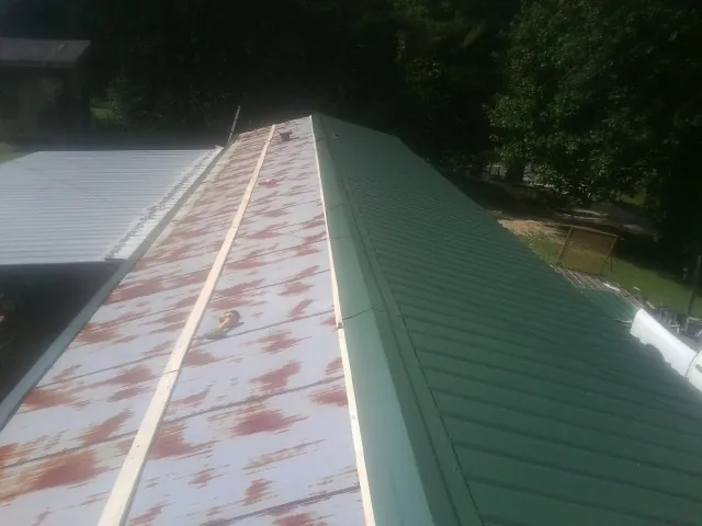 Old rusted panels beside newly installed green metal roofing — Wind Damage Roof Repair by Roofing Brothers in Whiteside
