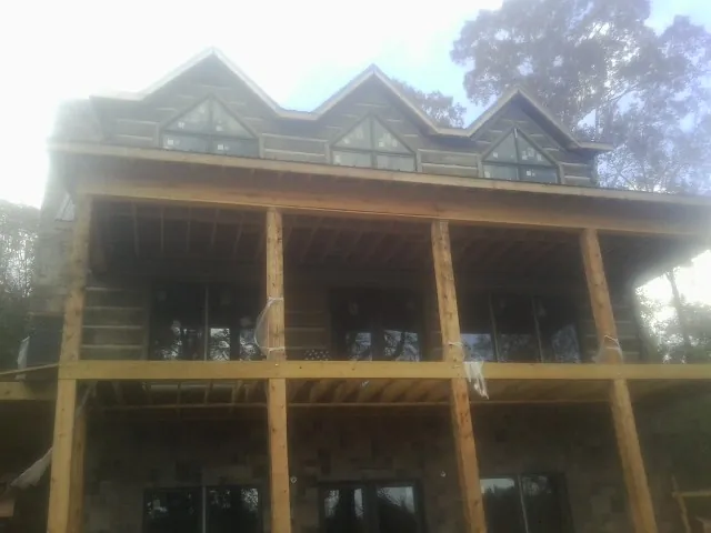 Dormers and porch framing on a large log home under construction — Roof Coating work by our crew in Whiteside