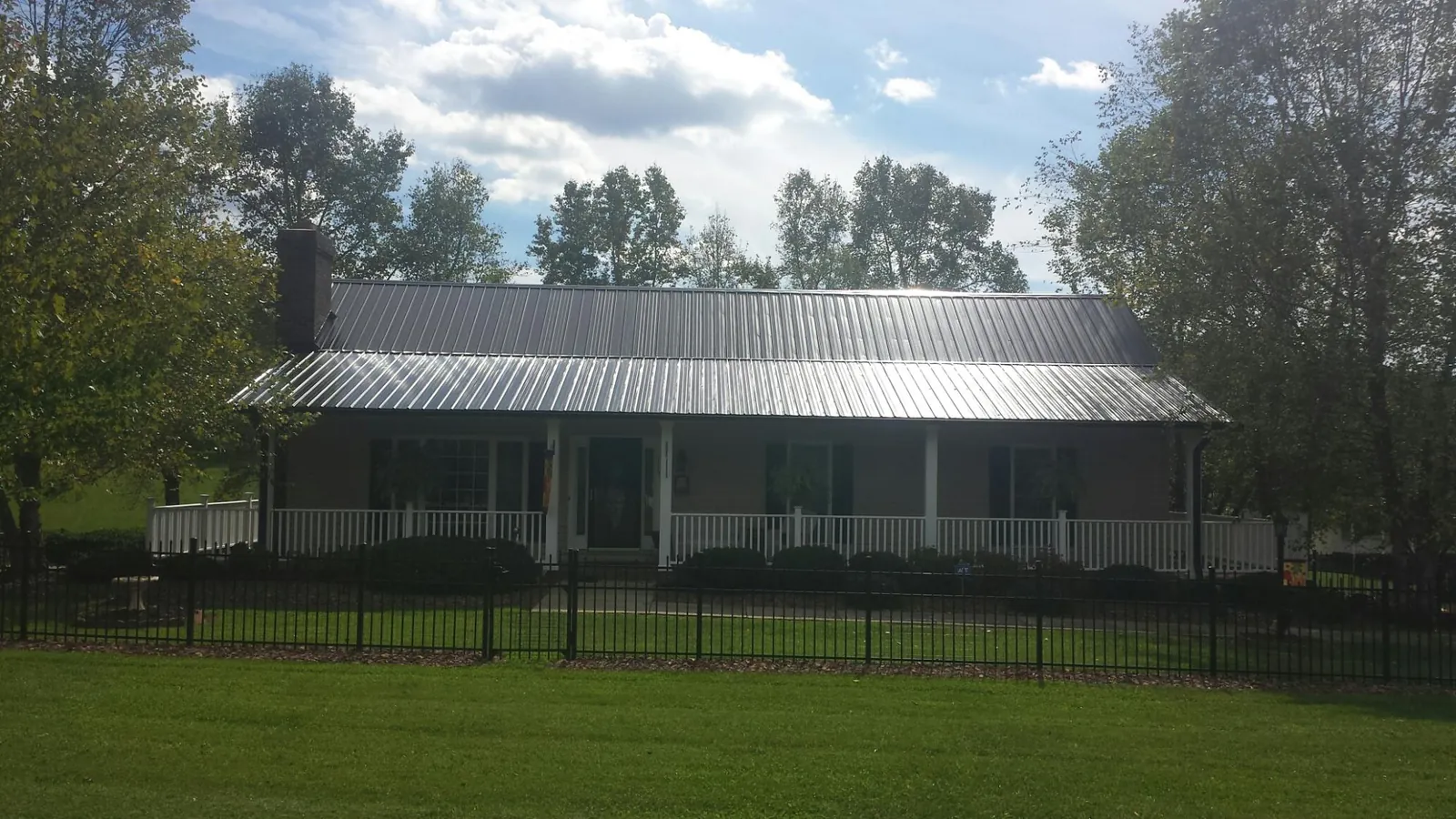 Gray metal roof on a brick ranch with a full width front porch — Gutter Guard Installation work by our crew in Whiteside