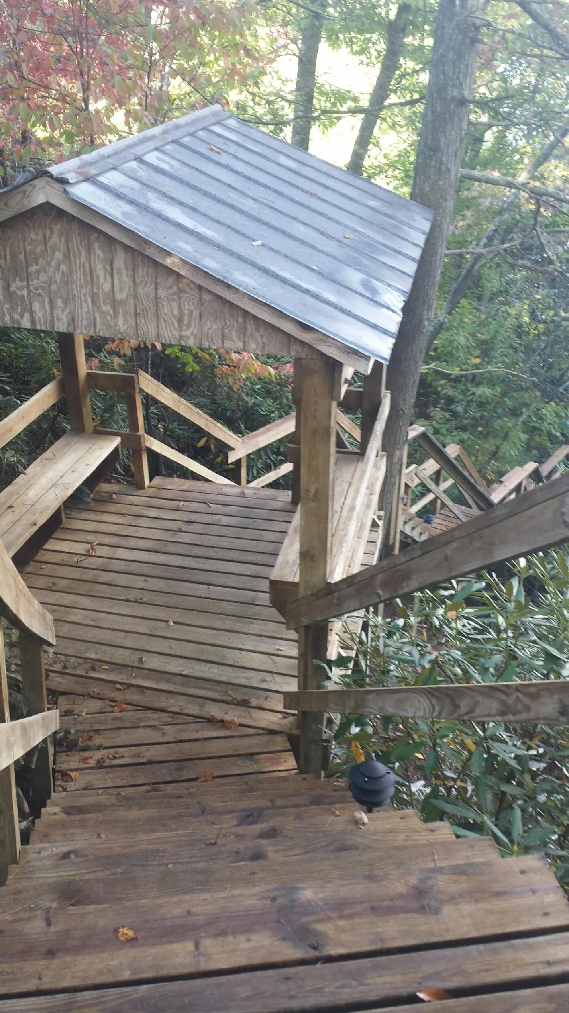 Metal roofed shelter over wooden steps on a wooded walkway — Skylight Repair & Installation work by our crew in Whiteside