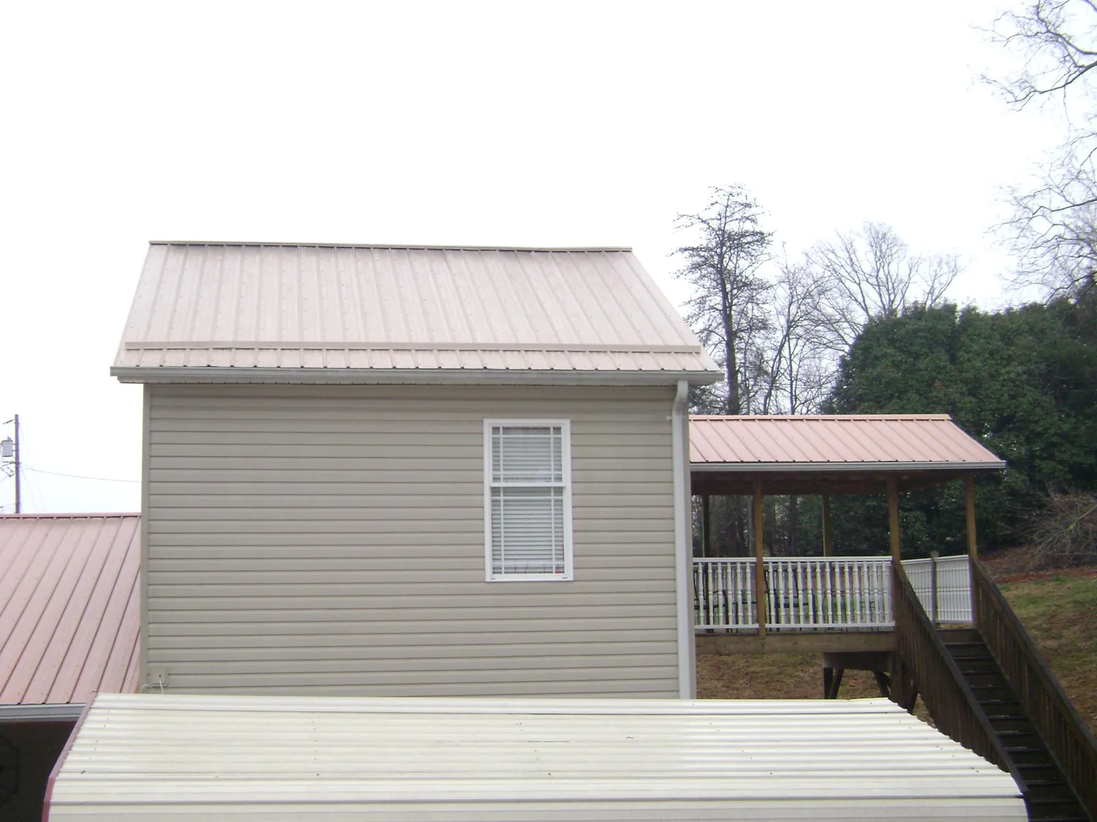 Tan metal roofs on a two story addition and attached porch, from a Roof Replacement job in Whiteside