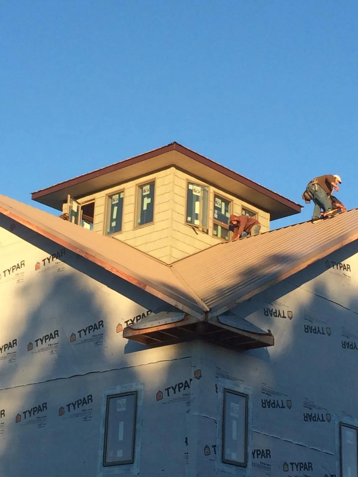 Roofers working around a rooftop cupola on a new metal roof at sunset — Roof Waterproofing in Whiteside by Roofing Brothers